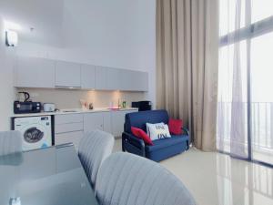 a living room with a blue chair and a kitchen at I-City 2-Bedroom - Great Value Homestay in Shah Alam