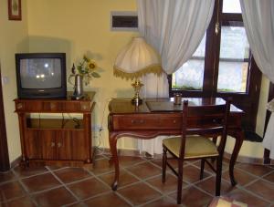 Zimmer mit einem Schreibtisch, einem TV, einem Tisch und einem Stuhl in der Unterkunft Apartment im englischen Stil mit Meerblick in Icod de los Vinos