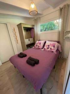 Un dormitorio con una cama grande con sábanas moradas y una ventana en La Cabane, en Le Bar-sur-Loup