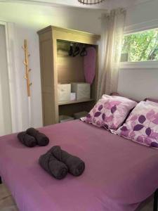 Una cama morada con dos toallas marrones. en La Cabane, en Le Bar-sur-Loup