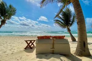 a cooler on a beach with palm trees and the ocean at The Beach Tulum Hotel in Tulum