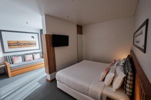 a bedroom with a bed and a flat screen tv at Hotel Praia Marina by RIDAN Hotels in Praia da Vitória