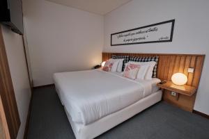 a bedroom with a large white bed with pillows at Hotel Praia Marina by RIDAN Hotels in Praia da Vitória