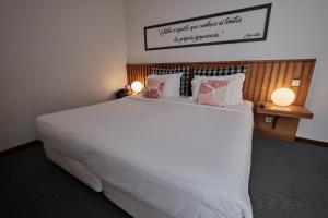 a bedroom with a large white bed with pillows at Hotel Praia Marina by RIDAN Hotels in Praia da Vitória
