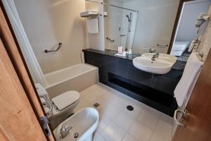a bathroom with a sink and a toilet and a tub at Hotel Praia Marina by RIDAN Hotels in Praia da Vitória