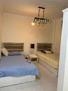 a bedroom with two beds and a chandelier at Gardenia city , Nasr city in Cairo