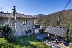 a small stone house with a mountain in the background at Casa de Aldea Menéndez in Cangas del Narcea