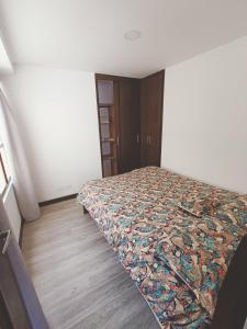 a bedroom with a bed with a quilt on it at Apartamento moderno en condominio Agualongo in Pasto
