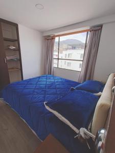 a bedroom with a blue bed and a window at Apartamento moderno en condominio Agualongo in Pasto