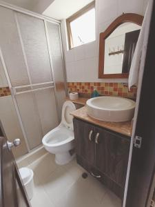 a bathroom with a toilet and a sink and a mirror at Apartamento moderno en condominio Agualongo in Pasto