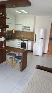 a kitchen with a refrigerator and a table in it at Praia Dourada SUÍTE ITAPARICA 1206 in Vila Velha