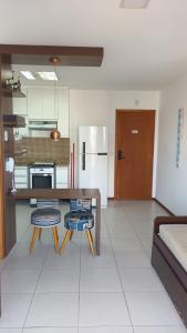 a kitchen with a table and chairs and a refrigerator at Praia Dourada SUÍTE ITAPARICA 1206 in Vila Velha