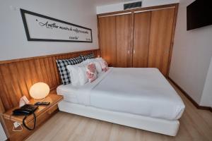 a bedroom with a large white bed and a table at Hotel Praia Marina by RIDAN Hotels in Praia da Vitória