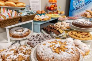 a table filled with different types of pastries and pies at Hotel Albachiara in Viareggio