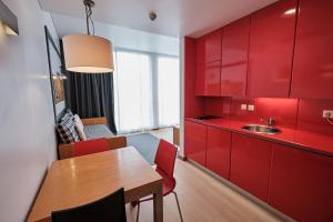 a kitchen with red cabinets and a wooden table at Hotel Praia Marina by RIDAN Hotels in Praia da Vitória
