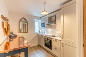 a kitchen with white cabinets and a counter at Luxury Chapel Apartment within City Walls in Chester