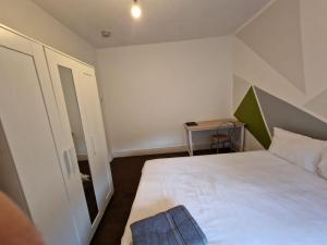 um pequeno quarto com uma cama branca e uma mesa em Brewery rd Double room em Plumstead