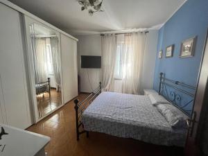 Dormitorio azul con cama y espejo en Casa Rossa, en San Leonardo