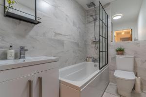 a white bathroom with a tub and a toilet and a sink at Luxury Chapel Apartment within City Walls in Chester