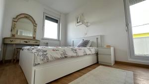 - une chambre blanche avec un lit et un miroir dans l'établissement Tranquil apartment across the bridge, à Novi Sad
