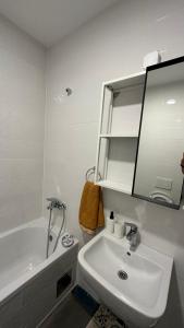 La salle de bains blanche est pourvue d'un lavabo et d'une baignoire. dans l'établissement Tranquil apartment across the bridge, à Novi Sad