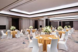 上海市にあるFour Points by Sheraton Shanghai Jiadingのテーブルと白い椅子のある宴会場、テーブルと白で満たされた部屋