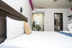 Un dormitorio con una gran cama blanca con una almohada. en Pa´Xa Mama Hotel Boutique, en Cancún