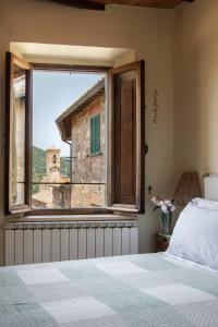 a bedroom with a bed and a large window at Il Borghetto - La Ghibellina Townhouse in Castelnuovo dellʼAbate