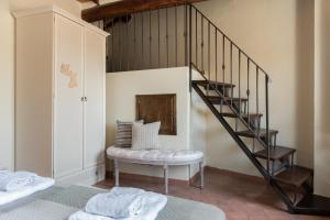 a room with a staircase and a bench with towels at Il Borghetto - La Ghibellina Townhouse in Castelnuovo dellʼAbate