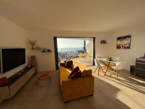 ein Wohnzimmer mit einem gelben Sofa und einem TV in der Unterkunft OPALE in Porticcio