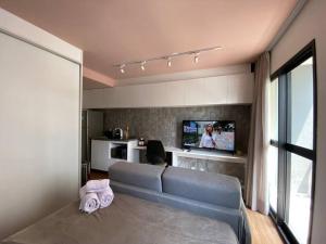 un salon avec un canapé et une télévision à écran plat dans l'établissement Colorful Windows - novo studio na Liberdade, à São Paulo