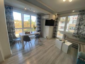 a living room with a table and chairs and a large window at Уютен нов апартамент - Стара Загора с две спални in Stara Zagora