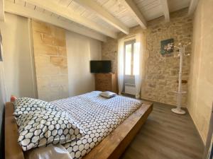 1 dormitorio con 1 cama en una habitación con una pared de piedra en Bienvenue au 6 - Calme et charme de la pierre., en Fourques