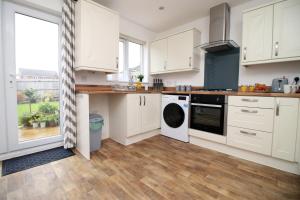 a kitchen with white cabinets and a large window at Beautiful Modern House with Free Parking in Swansea