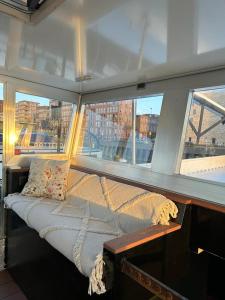 a bed on a boat in front of a window at WHEELHOUSE EUPHRATE HOUSEBOAT in Amsterdam