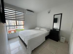 a bedroom with a bed and a mirror and a window at Hermoso y comodo apartamento con Aire acondicionado y parqueo privado en unidad residencial - Jamundi in Jamundí