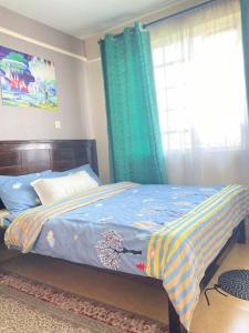 a bedroom with a bed with a blue comforter and a window at The Cream Loft in Eldoret