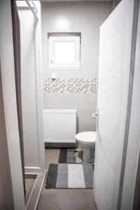a white bathroom with a toilet and a window at Prenoćište Lelić in Valjevo