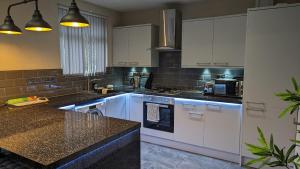uma cozinha com armários brancos e um balcão preto em Modernised 4 Bedroom Property Close To City Centre, Harehills Lane em Roundhay