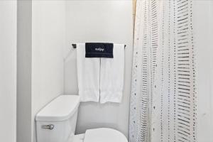 a white bathroom with a toilet and a shower curtain at Unit 5: Sun drenched studio with tranquil vibes in Billings
