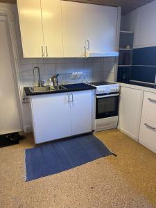 a kitchen with white cabinets and a sink and a stove at B & E Apartment in Huddinge