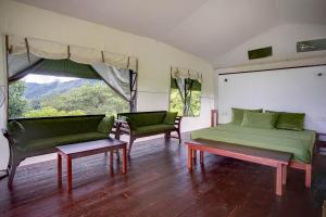a room with a bed and two chairs and a window at Bellway Chalets in Dedugala