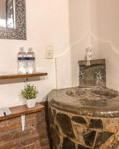un lavabo de piedra en una habitación con 2 botellas de agua en Calesa Real en Querétaro