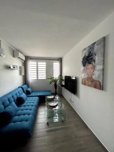 een woonkamer met een blauwe bank en een tv bij Appartement 42 in Fort-de-France