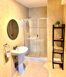 een badkamer met een douche, een wastafel en een spiegel bij Apartamentos Montes in Cuzco