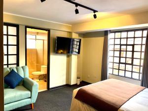Un dormitorio con una cama, un sofá y un televisor. en Apartamentos Montes, en Cusco
