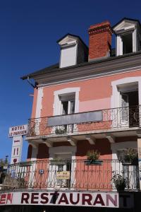 a red and white building with a balcony at Hôtel restaurant Le Parisien in Lourdes