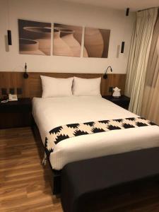 1 dormitorio con 1 cama grande con sábanas blancas y negras en Casa Tlaxcalli by Beddo Hoteles en Tlaxcala de Xicohténcatl