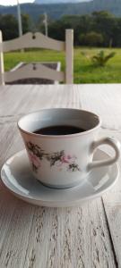 uma chávena de café sentada num prato numa mesa em Hostel e Pousada Vale Mirante da Rocha em Timbe do Sul