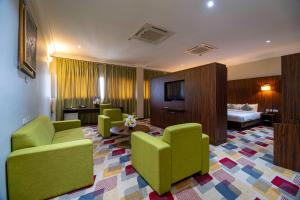 Alisa Hotel North Ridge في آكرا: غرفة بالفندق بها كراسي خضراء وسرير